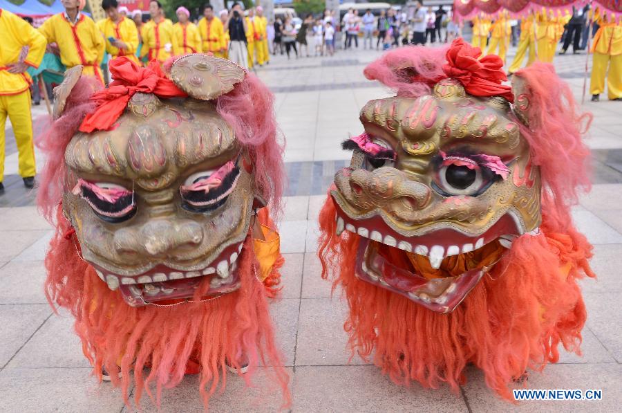 Folk artists perform a lion dance on a street in Qianjiang City, central China's Hubei Province, June 14, 2015. 