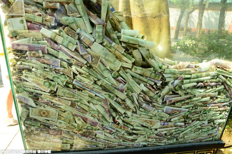 Bronze statues in Guangzhou scenic spot “swallowed” by banknotes and coins