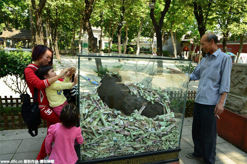 Bronze statues in Guangzhou scenic spot “swallowed” by banknotes and coins