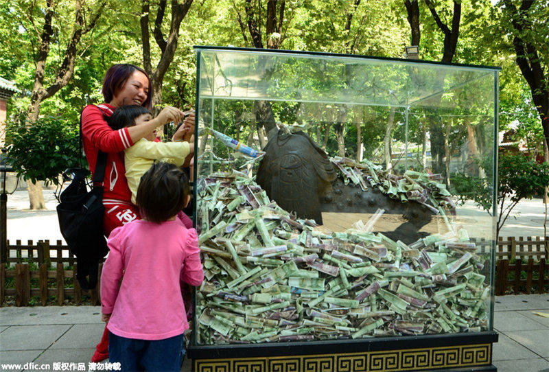 Bronze statues in Guangzhou scenic spot “swallowed” by banknotes and coins