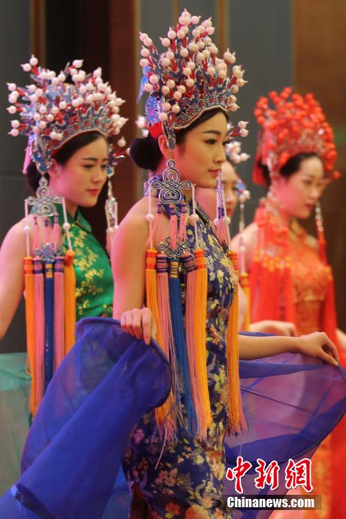 Models wearing phoenix coronet and cheongsam go down the runway