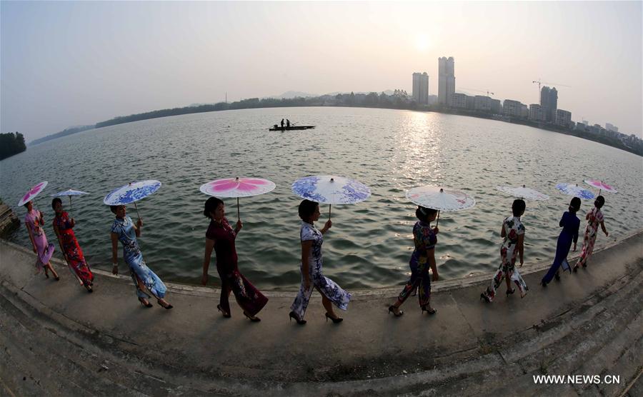 Ladies pose with umbrellas at a Qipao show by the Rongjiang river in Rong'an County, south China's Guangxi Zhuang Autonomous Region, Sept. 20, 2016. Qipao is a traditional Chinese dress. 