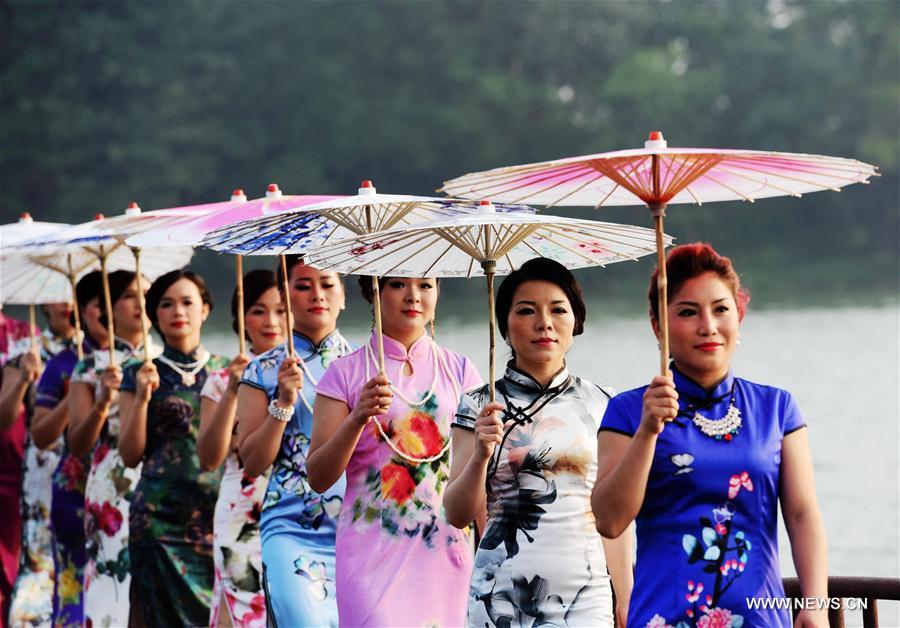 Ladies pose with umbrellas at a Qipao show by the Rongjiang river in Rong'an County, south China's Guangxi Zhuang Autonomous Region, Sept. 20, 2016. Qipao is a traditional Chinese dress. 