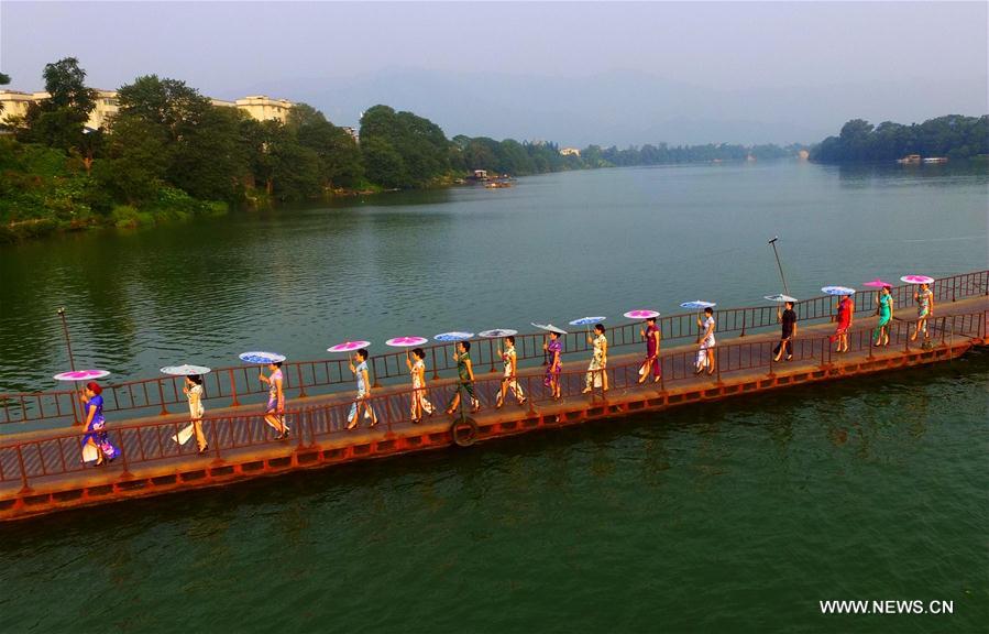 Ladies pose with umbrellas at a Qipao show by the Rongjiang river in Rong'an County, south China's Guangxi Zhuang Autonomous Region, Sept. 20, 2016. Qipao is a traditional Chinese dress. 