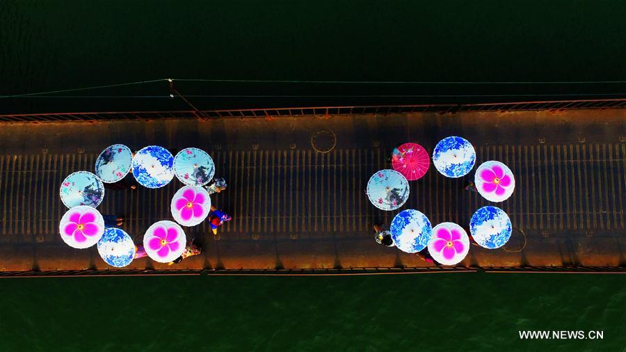 Ladies pose with umbrellas at a Qipao show by the Rongjiang river in Rong'an County, south China's Guangxi Zhuang Autonomous Region, Sept. 20, 2016. Qipao is a traditional Chinese dress. 