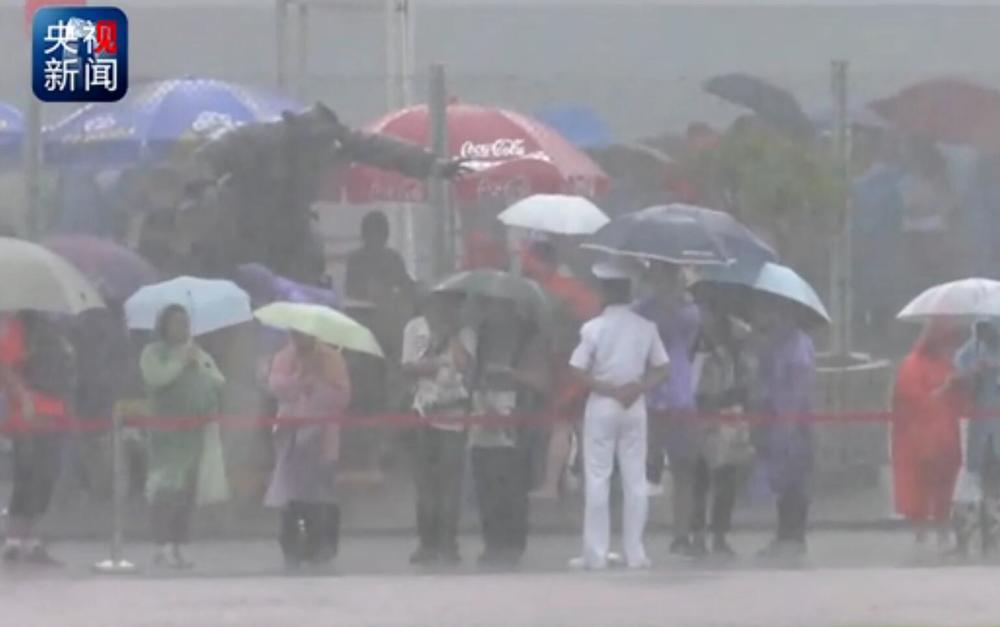 Hong Kong citizen holds umbrella for PLA guard in rainstorm