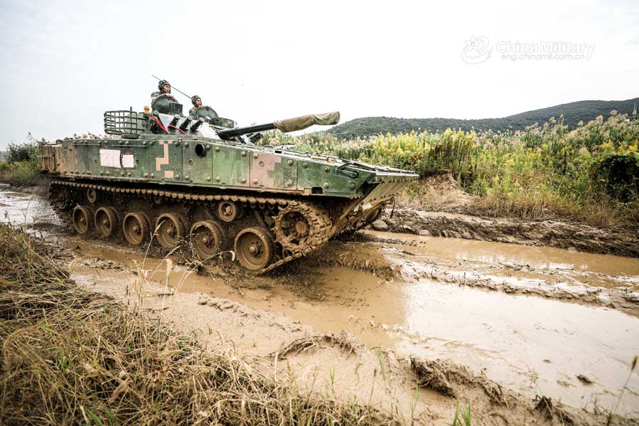 Infantry fighting vehicles drive through mire