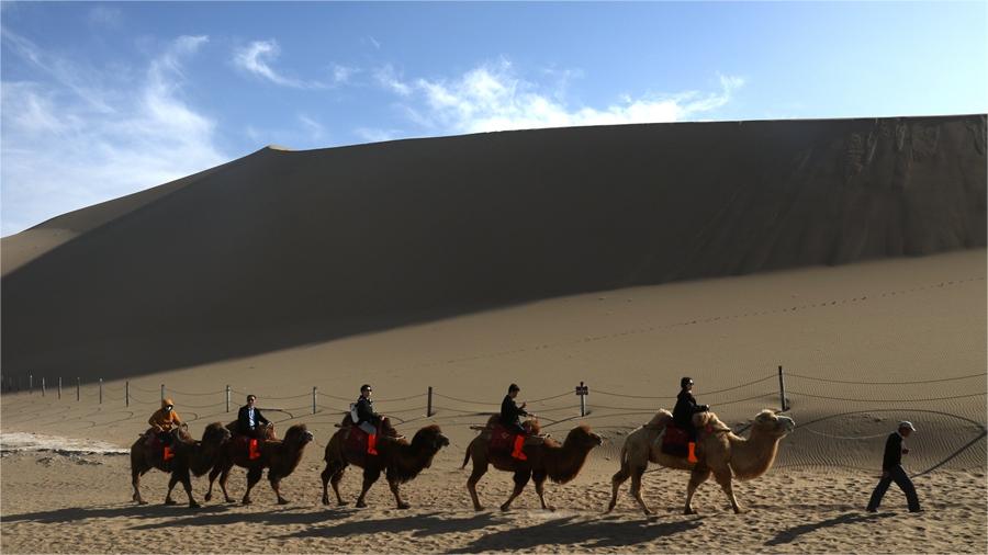 Tourists enjoy picturesque spring views of desert in Dunhuang, NW China's Gansu