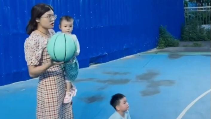 Mother shoots perfect three-pointer while cradling baby