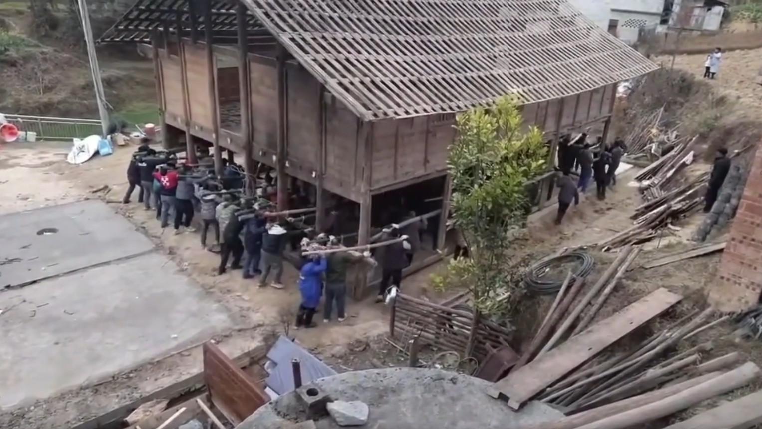 Villagers demonstrate strength in unity by moving a house together