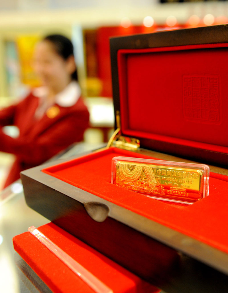 A staff worker shows off the gold bar for the Chinese year of the Snake in a Tianjin jewellery store on Nov. 4. This so-called Chinese zodiac gold bar debuts in the city and comes in five weight categories: 50g, 100g, 200g, 500g and 1,000g. (Xinhua)