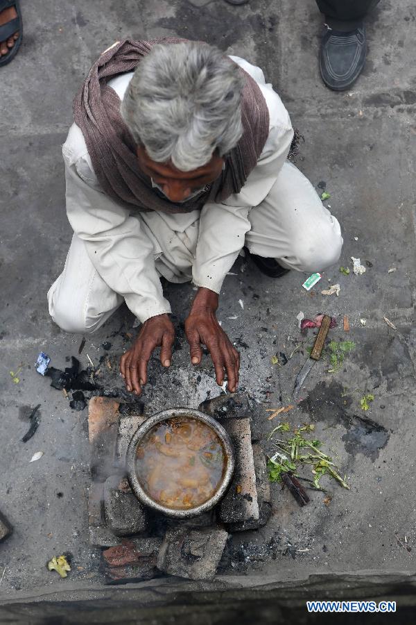 A rickshaw driver warms his hands near a cooking fire in East Patel Nagar, northern New Delhi, India, on Nov. 5, 2012. Rickshaw drivers' life is hard in the old city of New Delhi. (Xinhua/Li Yigang) 