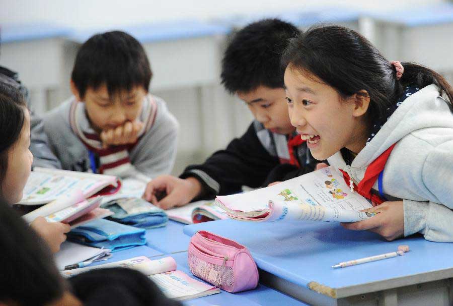 Ran Mengjie (1st R), whose parents are migrant workers, discusses with classmates at the Longta Experimental Elementary School in southwest China's Chongqing Municipality, Nov. 6, 2012. Among the 706 students at the Longta Experimental Elementary School, about 150 are children of migrant workers. A total of 665 elementary schools in the city proper of Chongqing have accepted children of migrant workers, according to the municipality's education authorities. Children of migrant workers can enjoy free education and other subsidies at those schools. (Xinhua/Li Jian) 