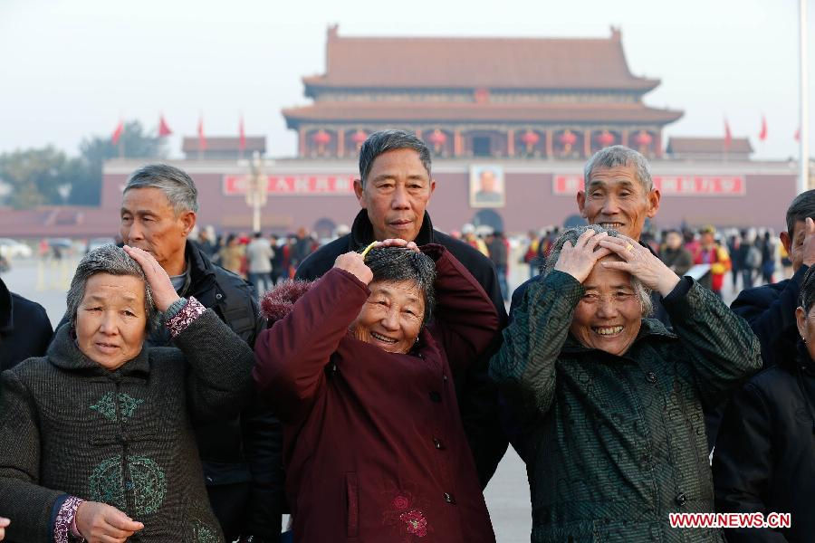 Bi Xiaoying, Lu Cuixiang and Wang Laiying (L-R) from east China's Anhui Province do up their hair as they pose for a group photo at the Tian'anmen Square in Beijing, capital of China, Nov. 7, 2012. Tourists from across the country and local residents watched the national flag-raising ceremony at the square early Nov. 7, one day ahead of the opening of the 18th National Congress of the Communist Party of China. (Xinhua/Jin Liwang)