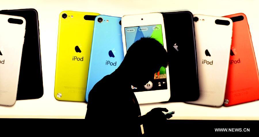 A pedestrian walks past a billboard outside an Apple products store in south China's Hong Kong, Nov. 7, 2012. Apple products like iPhone 5, iPad mini sell well after they appeared on the market in Hong Kong in September last year.(Xinhua/Chen Xiaowei)