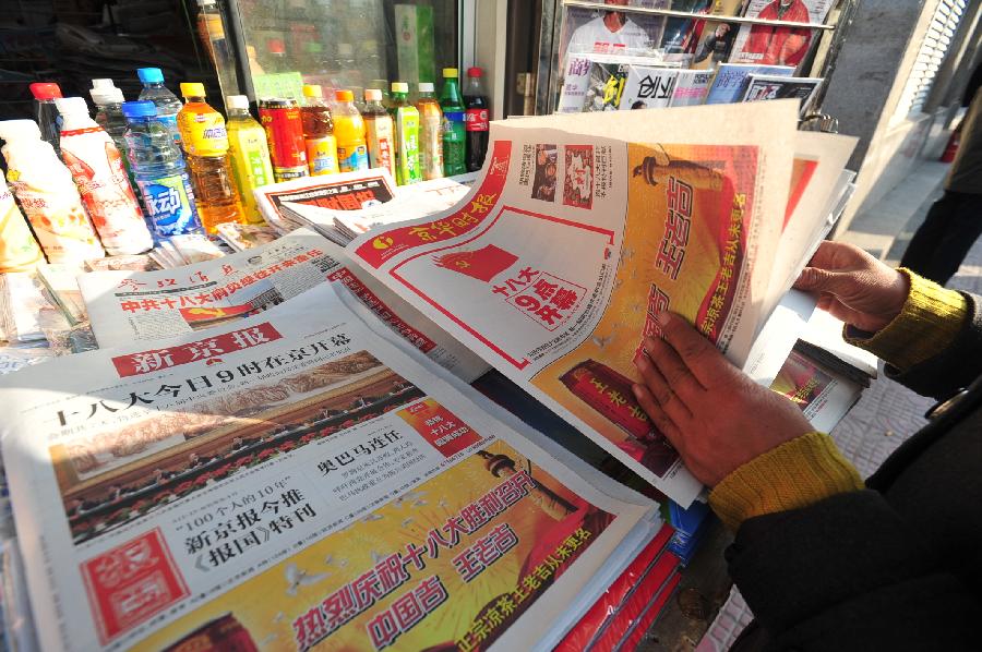 A pedestrian watches newspaper reporting the opening ceremony of the 18th National Congress of the Communist Party of China (CPC) in Beijing, capital of China, Nov. 8, 2012. The 18th CPC National Congress was opened in Beijing on Thursday. (Xinhua/Liu Changlong)