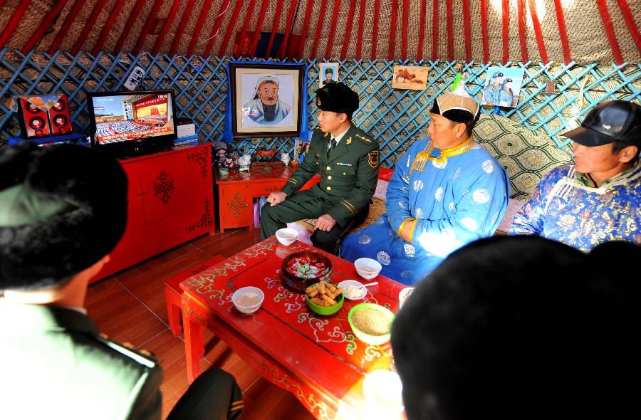 Police officers, along with herdsmen, watch live TV report on the opening ceremony of the 18th National Congress of the Communist Party of China (CPC) in Sonid Youqi Banner, north China's Inner Mongolia Autonomous Region, Nov. 8, 2012. The 18th CPC National Congress was opened in Beijing on Thursday. (Xinhua/Ren Junchuan)