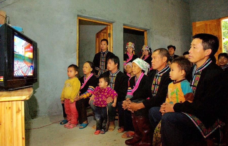 People of Yao ethnic group watch live TV report on the opening ceremony of the 18th National Congress of the Communist Party of China (CPC) in Qibainong Township, south China's Guangxi Zhuang Autonomous Region, Nov. 8, 2012. The 18th CPC National Congress was opened in Beijing on Thursday. (Xinhua/Zhang Ailin)