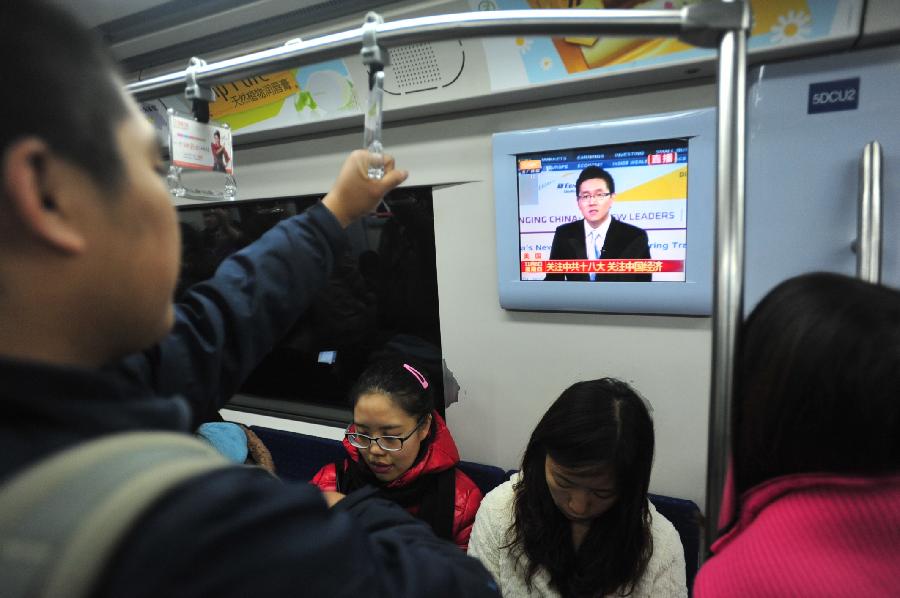 Subway passengers watch TV reporting the opening ceremony of the 18th National Congress of the Communist Party of China (CPC) in Beijing, capital of China, Nov. 8, 2012. The 18th CPC National Congress was opened in Beijing on Thursday. (Xinhua/Liu Changlong)