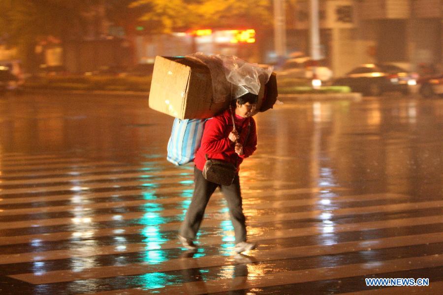 A citizen carrying luggage walks in the rain on Shengli Road of Yantai City, east China's Shandong Province, Nov. 10, 2012. A strong cold snap brought rainfall and wind to the coastal city, causing a fall in temperature. (Xinhua/Shen Jizhong)