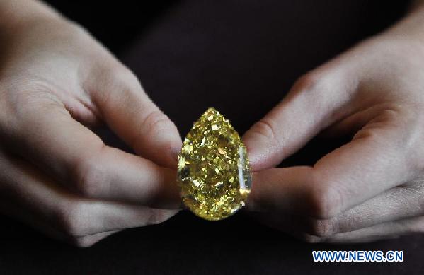 A model presents the Sun-Drop Diamond to meida at a hotel in Geneva, Switzerland, Nov. 9, 2011. The Sun-Drop is a sensational fancy vivid yellow pear-shaped diamond weighing 110.03 carats and is known as the largest pear-shaped fancy vivid yellow diamond in the world. (Xinhua/Yu Yang)