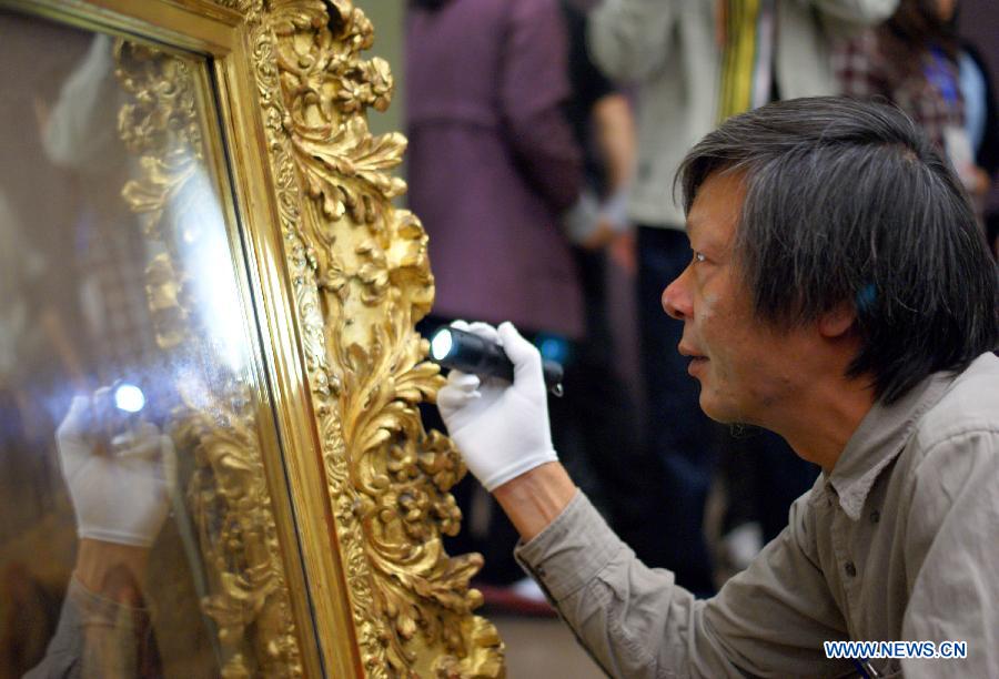 An expert checks the condition of Miller's masterpiece "Gleaners" during the exhibition arrangement of "Millet, Courbet and French Naturalism: Masterpieces from Musee d'Orsay" at the China Art Meseum in east China's Shanghai, Nov. 12, 2012.  (Xinhua/Ren Long) 