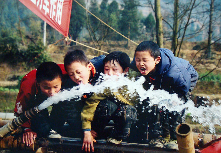 The pupils in arid area are delighted to see water spewing out of a newly drilled well. (People’s Daily Online/ Jiang Jianhua)  