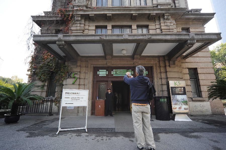 A visitor takes photo at the gate of the former site of Shanghai Art Museum in east China's Shanghai Municipality, Nov. 11, 2012.