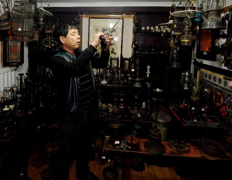 Tong Fucun looks at a piece of his collection in Taiyuan, capital of north China's Shanxi Province, Nov.11, 2012. (Xinhua/Yan Yan) 