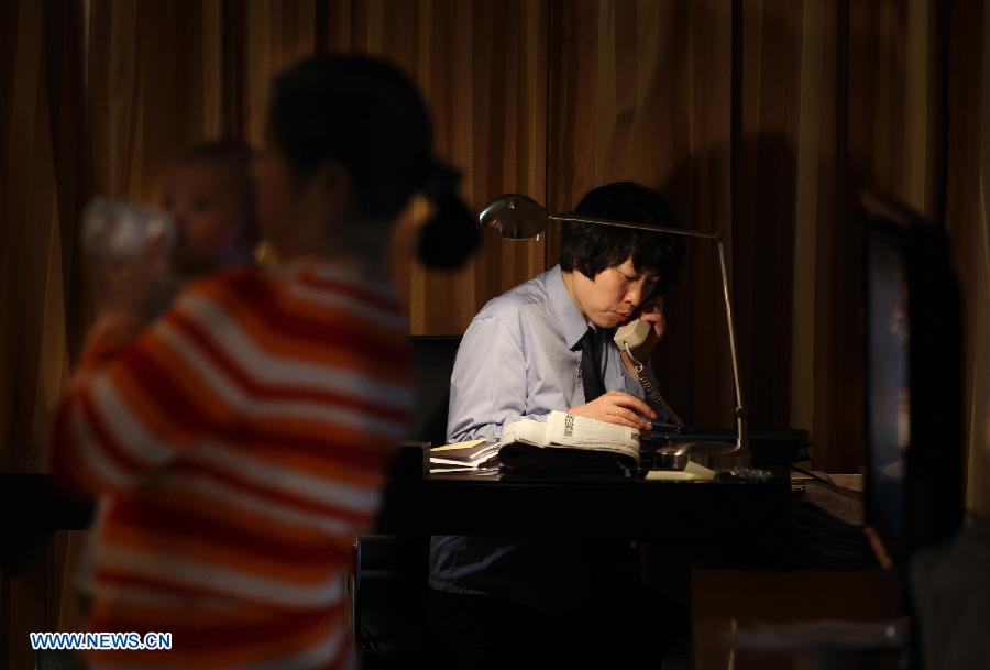 Jiang Min, a delegate to the 18th National Congress of the Communist Party of China (CPC), takes a call at her hotel room while a nanny helps her to take care of the baby in Beijing, capital of China, Nov. 13, 2012.(Xinhua/Jin Liwang)