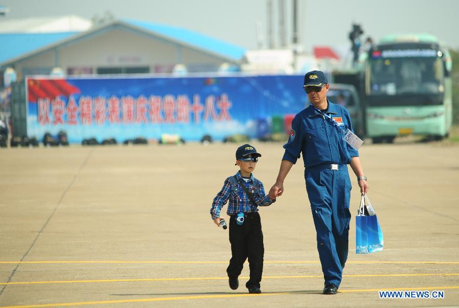 A soldier brings a child to take part in the 9th China International Aviation and Aerospace Exhibition in Zhuhai, south China's Guangdong Province, Nov. 13, 2012. Some 650 manufactures at home and abroad attended the six-day airshow kicked off on Tuesday, which was expected to receive 400,000 visitors. (Xinhua/Yang Guang)