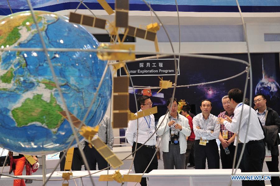 Visitors look at a model simulated the Beidou Satellite Navigation System displayed by the China Aerospace Science and Technology Corporation, during the 9th China International Aviation and Aerospace Exhibition in Zhuhai, south China's Guangdong Province, Nov. 13, 2012. Some 650 manufactures at home and abroad attended the six-day airshow kicked off on Tuesday, which was expected to receive 400,000 visitors. (Xinhua/Yang Guang)