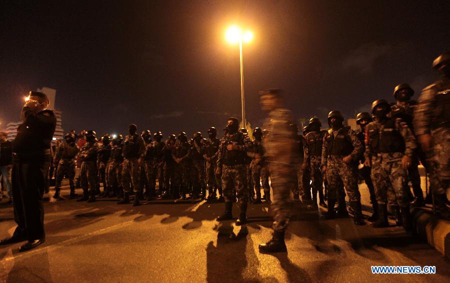 Jordanian gendarmerie policemen stand guard as protesters hold a demonstration following an announcement that Jordan would raise fuel prices, including a hike on cooking gas, in Amman, Jordan, Nov. 13, 2012. At least ten policemen were shot and four other civilians injured during riots across Jordan late Tuesday and Wednesday after the government ended fuel subsidies, the state-run Petra news agency reported. (Xinhua/Mohammad Abu Ghosh)