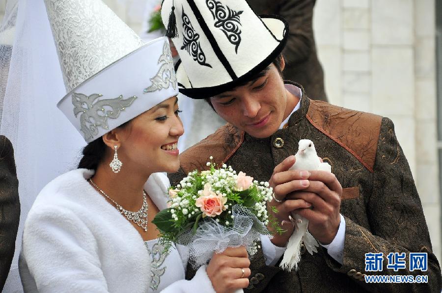 Kyrgyz brides and grooms lay flowers at the Eternal Flame before a mass wedding ceremony in Bishkek, Kyrgyzstan on May 13, 2011. (Xinhua/Luo Man)