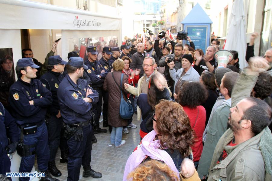 Police officers stand guard at the entrance of shops which remain open during the general 24 hours strike in Malaga, Spain, Nov. 14, 2012. The strike takes place in several areas of the country.(Xinhua)