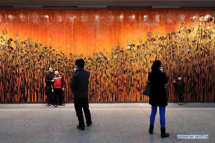 Passengers take souvenir photos in front of a public artwork at Wulin Plaza Station of the soon-to-open Metro Line 1 in Hangzhou, capital of east China's Zhejiang Province, Nov. 18, 2012. 600,000 residents and journalists are invited for a test ride from Sunday to Wednesday on the newly built metro line. (Xinhua/Ju Huanzong) 