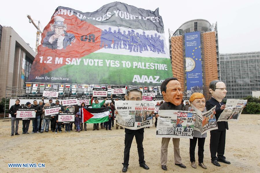 Activists wearing giant heads of French President Francois Hollande, German Chancellor Angela Merkel, British Prime Minister David Cameron and Spanish Prime Minister Mariano Rajoy (front R to L) attend a rally with a huge palestinian flag in front of EU headquarters in Brussels, Belgium, Nov. 19, 2012. Demonstrators installed the giant flag to urge EU backing the Palestinian membership in the United Nations. (Xinhua/Zhou Lei) 