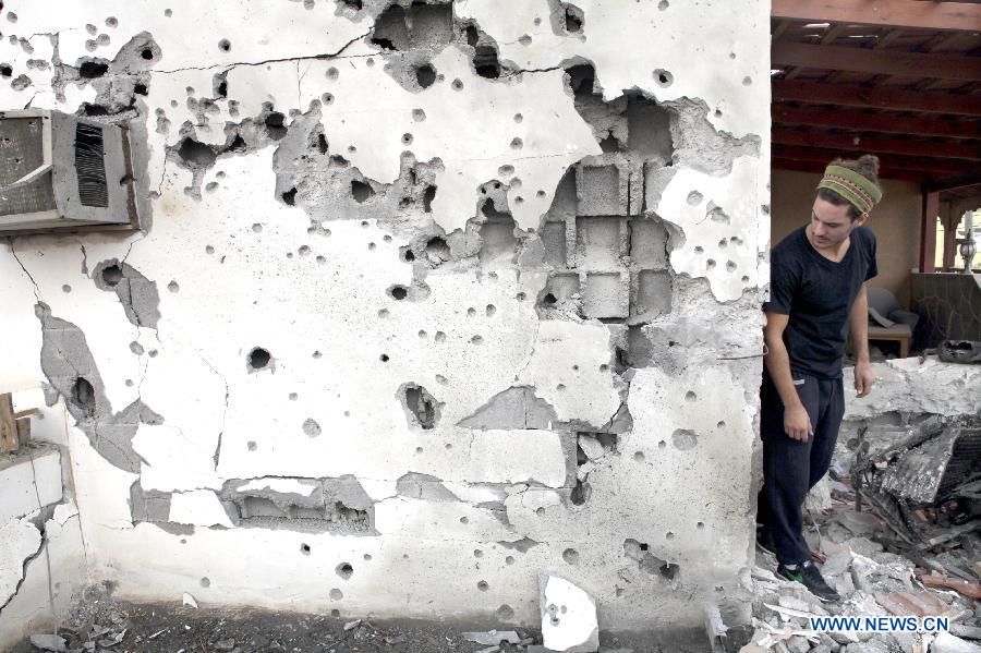 Ran Zohar, an Israeli resident, looks at his damaged house in Ofakim, south Israel, after being hit by a rocket fire from Gaza on Nov. 19, 2012. (Xinhua/Ariel Jerozolimski) 