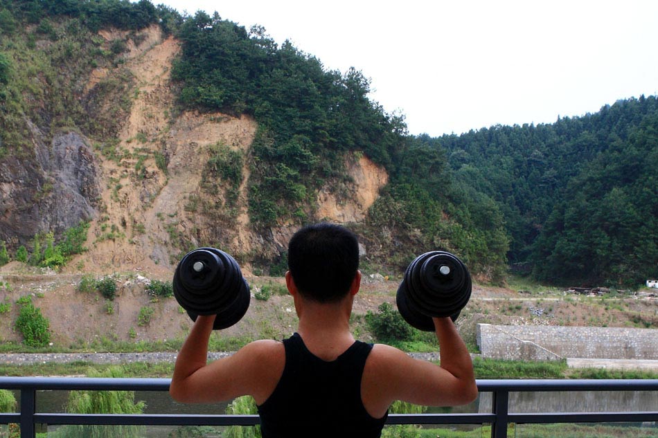 Wen Xin takes some exercise at work on the balcony of his studio in Shexian County of east China's Anhui Province, Aug. 7, 2012. (Xinhua/Xu Zijian)