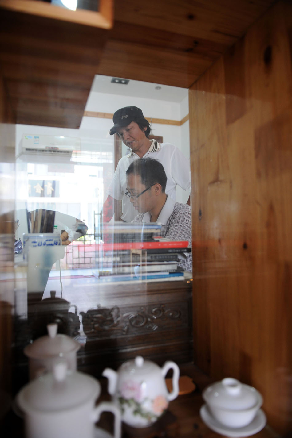 Li Bin (back) instructs a student to draw on a porcelain plate at a workroom in Jingdezhen, east China's Jiangxi Province, Aug. 18, 2012. (Xinhua/Zhang Ruiqi)