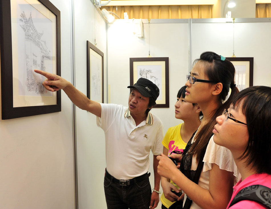 Li Bin (1st L) introduces his works during a solo exhibition held in southeast China's Taiwan, Sept. 17, 2012. (Xinhua/Wu Ching-teng)