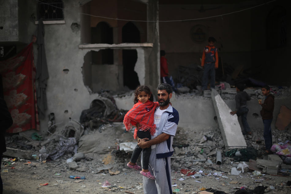 A Palestinian girl returns home which has been destroyed by air strikes with her father, in a refugee camp in the northern part of Gaza City, on Nov. 17, 2012. (Photo/Xinhua)