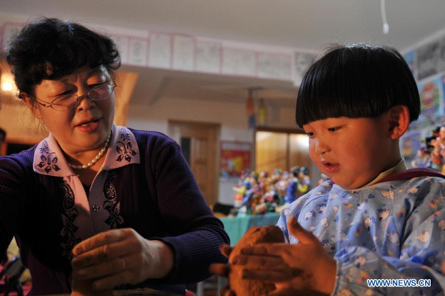 Li Lingxiu teaches a child to make clay sculptures in Lanzhou, capital of northwest China's Gansu Province, Nov. 20, 2012. The retired worker Li Lingxiu created 30 clay sculptures of characters in the ancient Chinese novel classic "A Dream of the Red Chamber". (Xinhua/Chen Bin) 