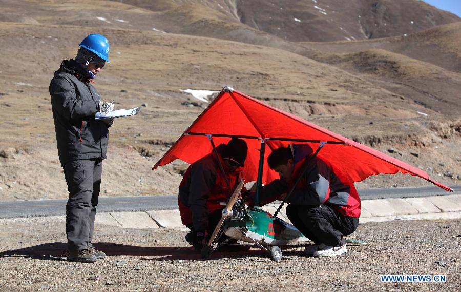 Technicists from the Shandong Electric Power Research Institute (SEPRI) examine an unmanned aircraft which is designed to inspect power transportation lines in regions of high altitude, during a test in Qinghai, a province on the Qinghai-Tibet Plateau, northwest China, Nov. 20, 2012. A research team of the SEPRI has recently conducted a flight test of unmanned aircrafts over the ground with altitude of 4,500 meters, which marks the end of the first round of the unmanned aircraft test project for inspecting power transportation lines on plateaus. (Xinhua) 