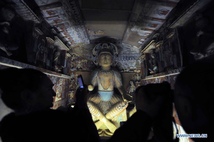 Visitors take photos in front of the duplicate of an ancient cave at "The Colors of Dunhuang: A Magic Gateway to the Silk Road" held in Mimar Sinan University in Istanbul of Turkey, on Nov. 20, 2012. The Exhibition kicked off here on Tuesday. (Xinhua/Ma Yan)