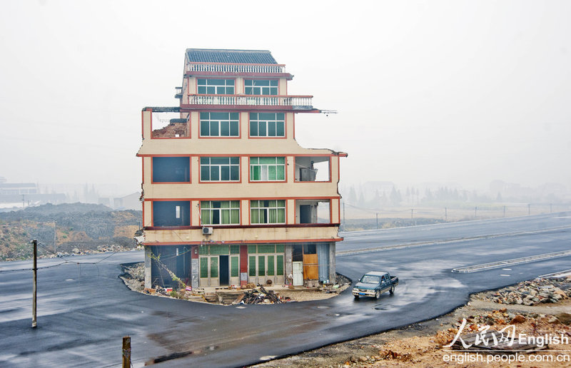 A five-story house stands in the middle of the road to the Railway Station of Wenling．People who are dissatisfied with the relocation compensation still live inside. Vehicles have to bypass the house to get through although the road has not been put into use. (CFP)