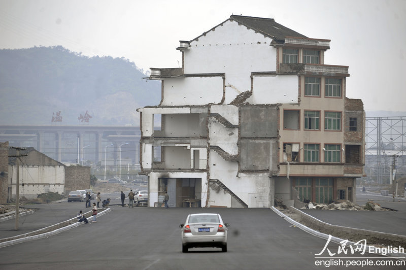 A five-story house stands in the middle of the road to the Railway Station of Wenling．People who are dissatisfied with the relocation compensation still live inside. Vehicles have to bypass the house to get through although the road has not been put into use. (CFP)