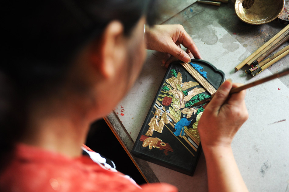 Hong Wenhao, a skilled worker in Xiang Shengli's inksticks factory, outline in gold color for a inkstick in Shexian County of east China's Anhui Province, Aug. 11, 2012. (Xinhua/Du Yu)