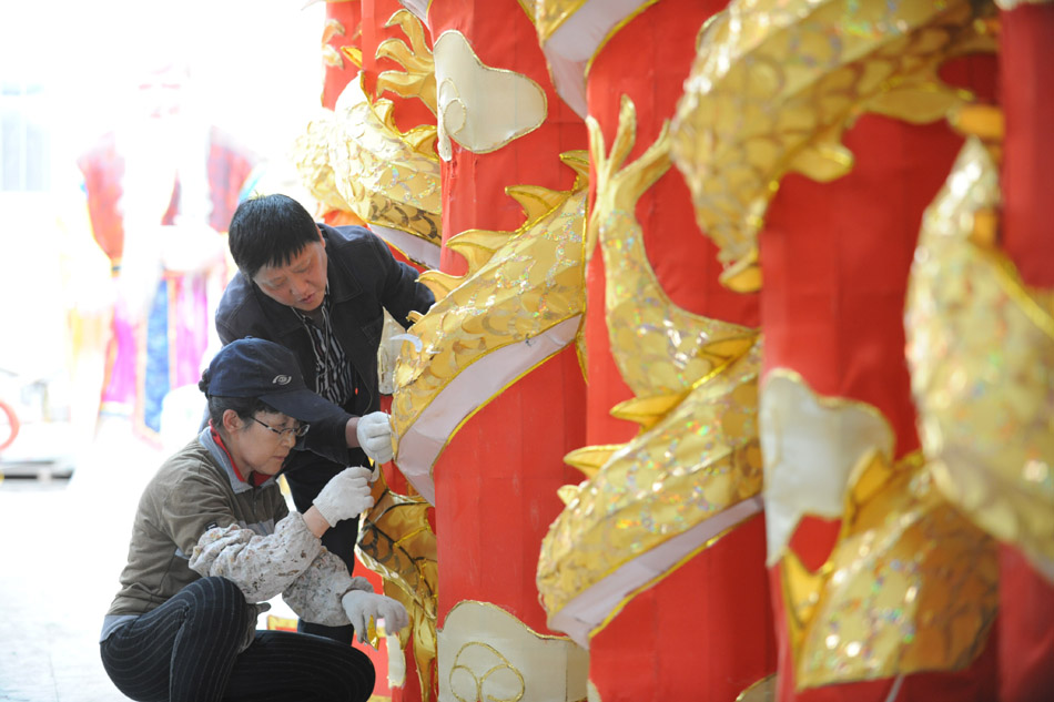 Sun Yubo (back) helps an worker while making festival lanterns at his workshop in Yangzhou, east China's Jiangsu Province, April 27, 2012. (Xinhua/Zhang Ruiqi)