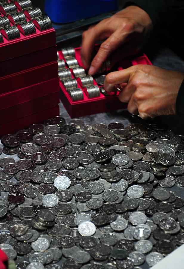 A staff member at the cash center of the Taicang Public Bus Company sorts coins in Taicang, east China's Jiangsu Province, Nov. 18, 2012. Each day, staff members at the cash center of the Taicang Public Bus Company need to sort out notes and coins collected from all bus fare boxes of the company. It takes four hours on average to finish a day's work: the total earnings of 52 bus lines. (Xinhua/Ji Haixin)